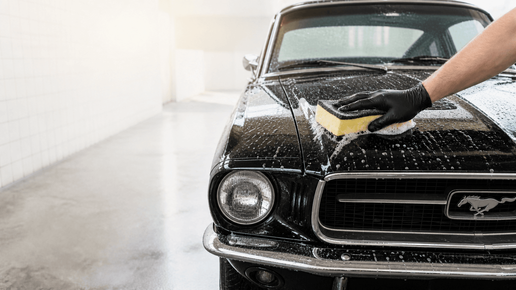 Ruční mytí černého klasického Fordu Mustang houbou
